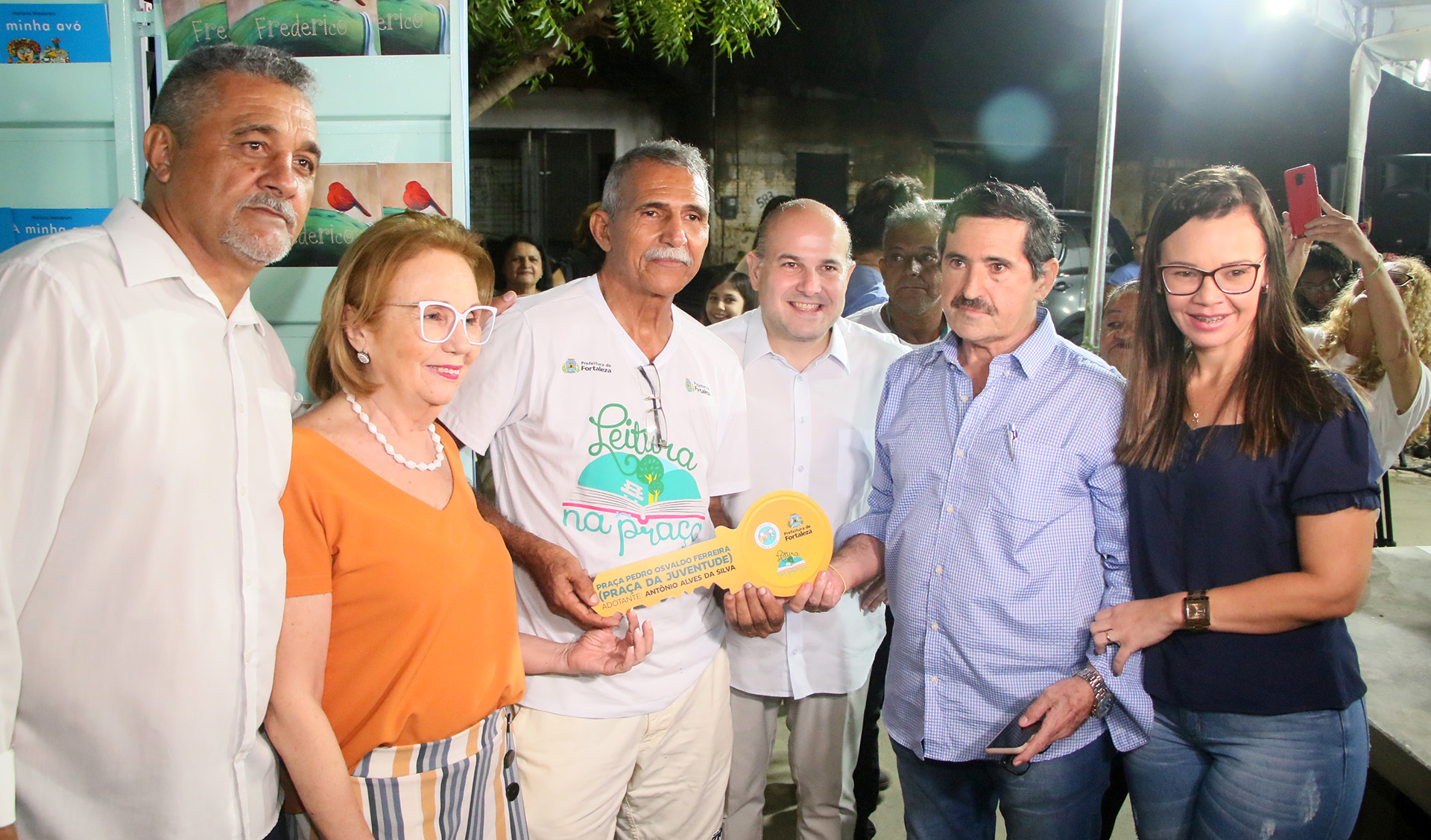 prefeito e outras pessoas em pé segurando uma chave gigante e sorrindo para a foto